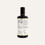 A dark glass bottle of olive oil with a black cap, showing the back of the label with nutrition facts and ingredients, on a white background.