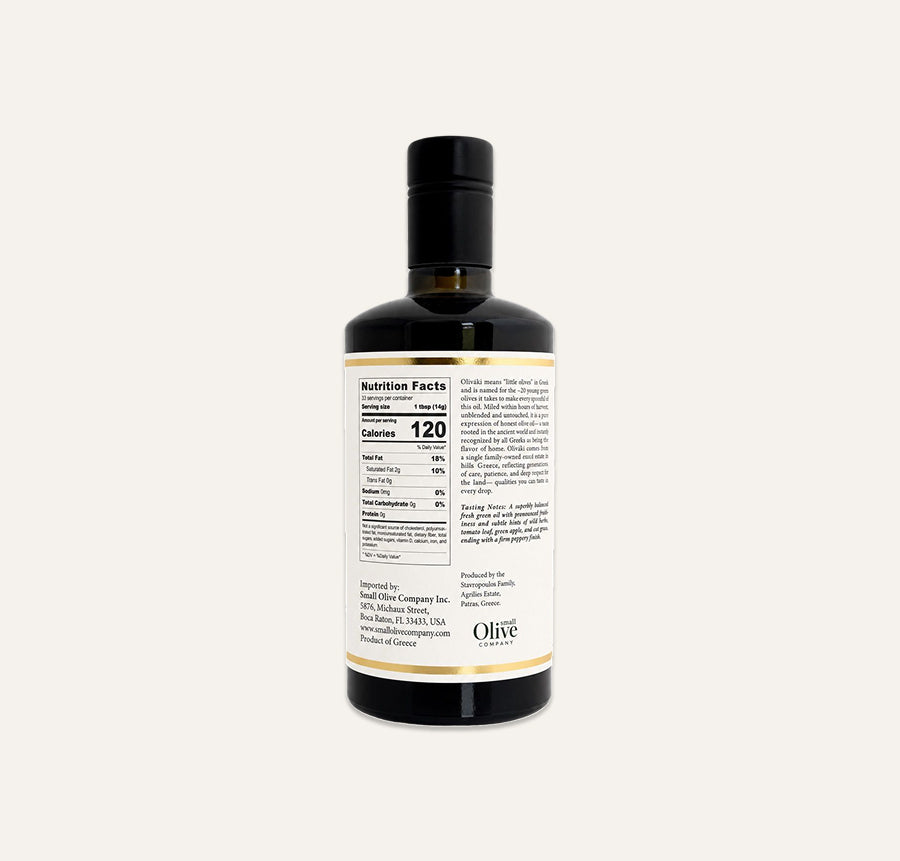 A dark glass bottle of olive oil with a black cap, showing the back of the label with nutrition facts and ingredients, on a white background.