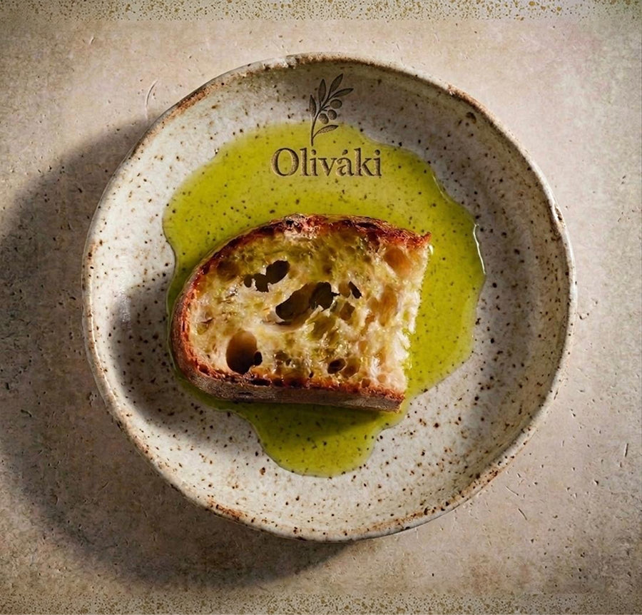 Toasted bread slice drizzled with Oliváki Greek extra virgin olive oil on a ceramic plate.