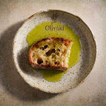 Toasted bread slice drizzled with Oliváki Greek extra virgin olive oil on a ceramic plate.