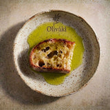 Toasted bread slice drizzled with Oliváki Greek extra virgin olive oil on a ceramic plate.
