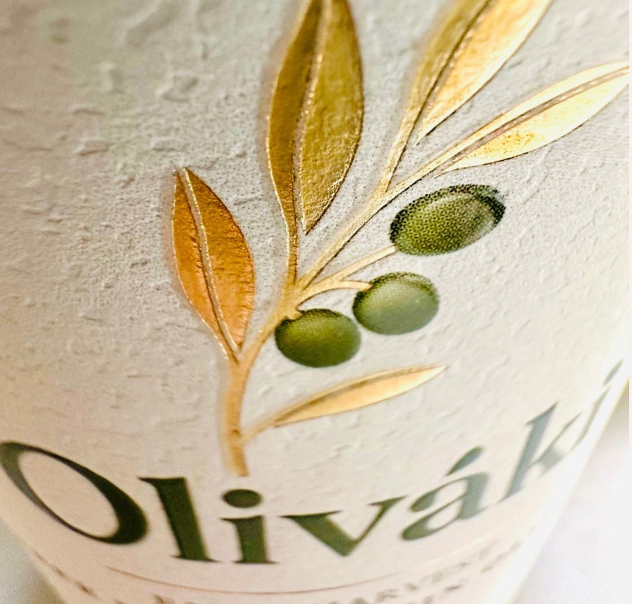 Close-up of Oliváki Greek Extra Virgin Olive Oil bottle featuring a gold olive branch design.