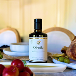 Oliváki Early Harvest Greek Extra Virgin Olive Oil bottle on a Mediterranean dining table.