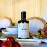 Oliváki Early Harvest Greek Extra Virgin Olive Oil bottle on a Mediterranean dining table.