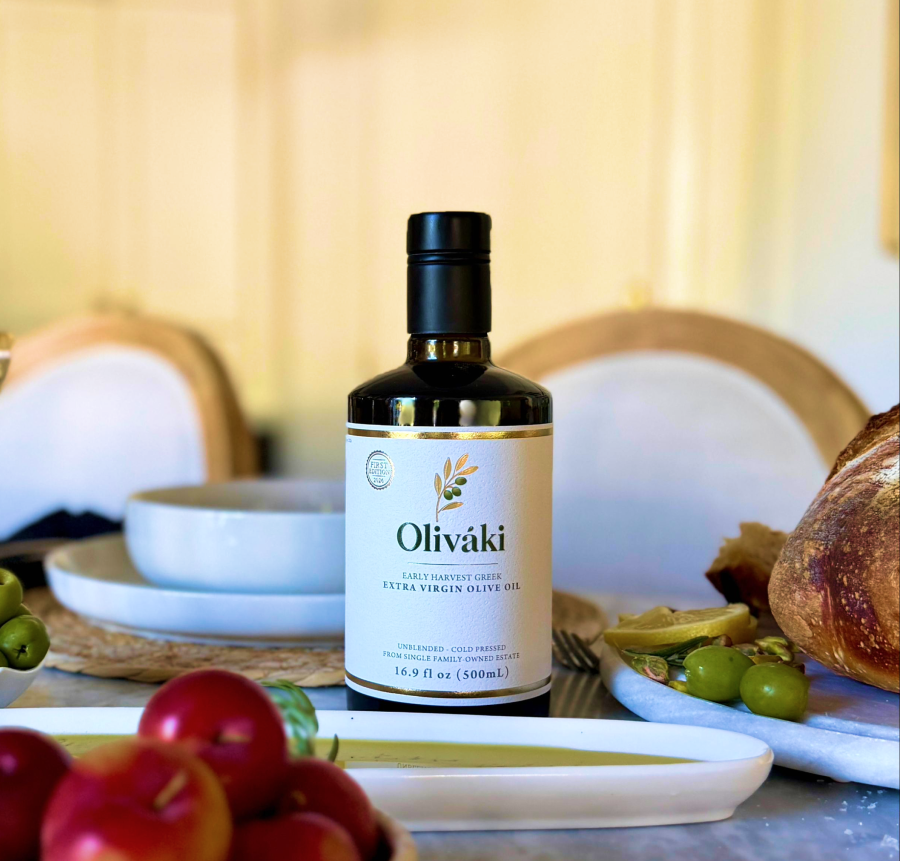 Oliváki Early Harvest Greek Extra Virgin Olive Oil bottle on a Mediterranean dining table.