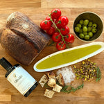 Oliváki Greek extra virgin olive oil served with sourdough bread, tomatoes, and pistachios.
