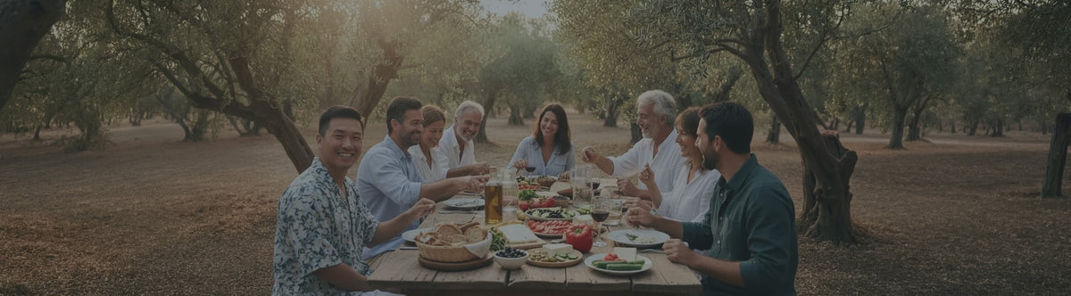 A group of friends enjoying an outdoor Mediterranean dinner in an olive grove.